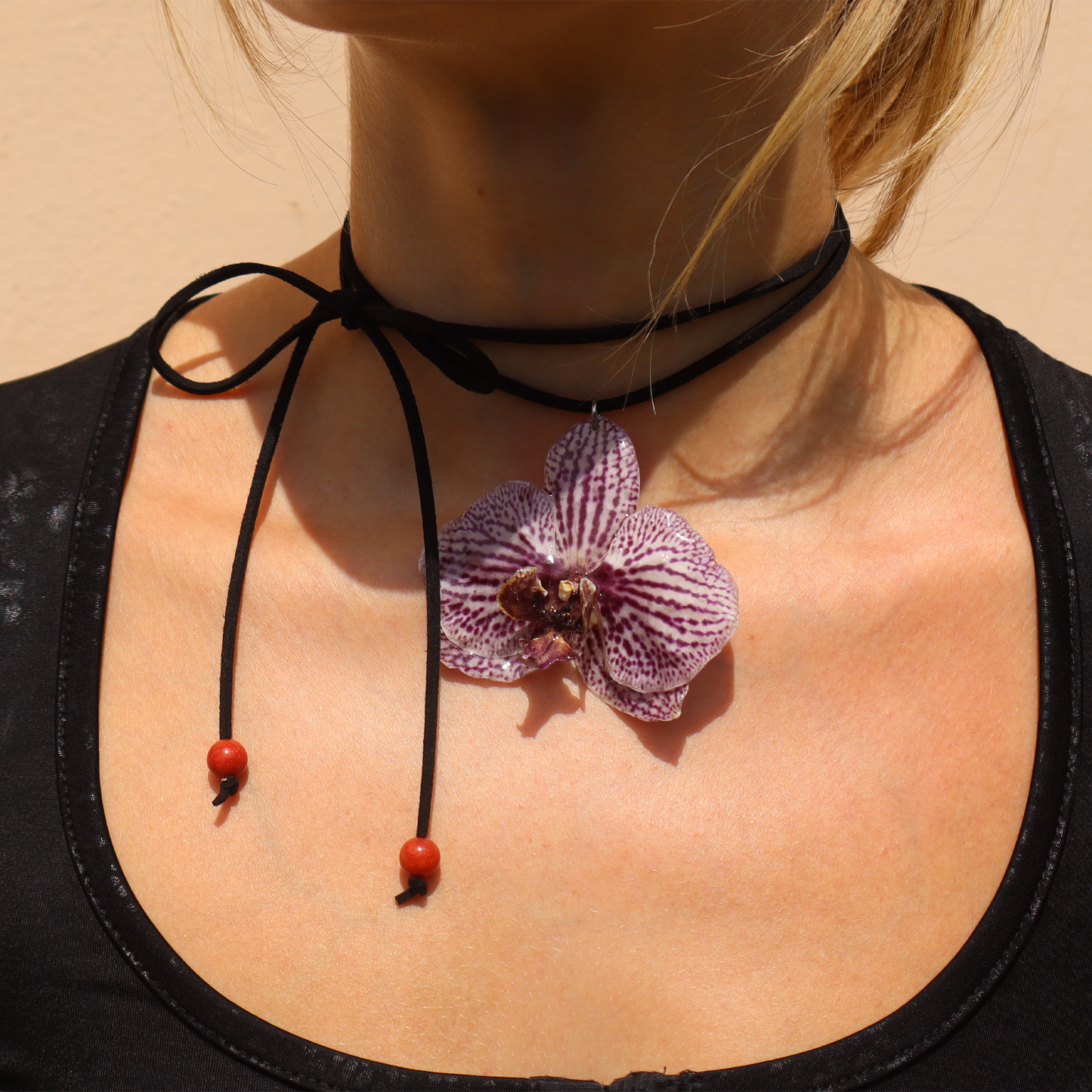 Mujer llevando choker exótico, joyería de diseño artesanal con flor de orquídea blanca y violeta natural

