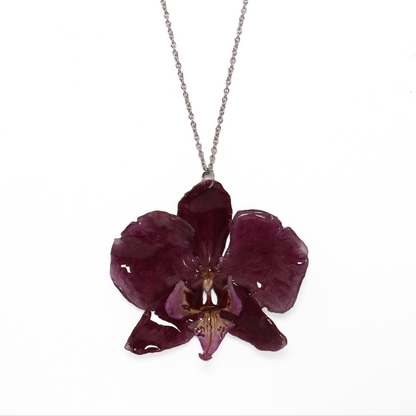 Collar violeta, joyería de diseño artesanal con flor de orquídea natural sobre fondo blanco
