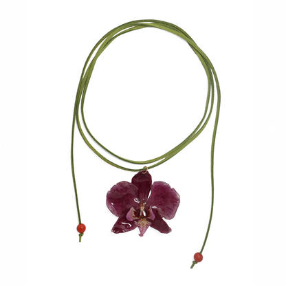 Choker violeta artesanal con flor de orquídea natural sobre fondo blanco
